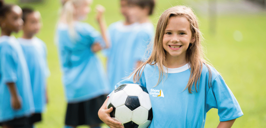image of a girl with a soccer ball held in her hand 